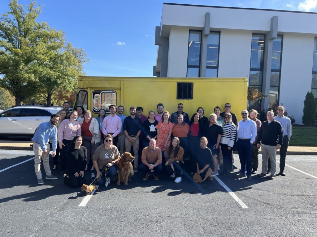a group of people posing for a photo in front of a yellow truck